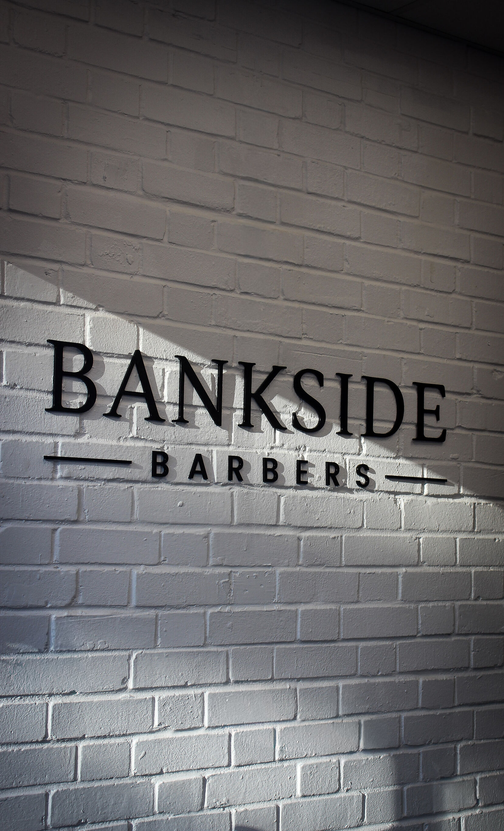 BANKSIDE BARBERS lettering on the painted brick wall